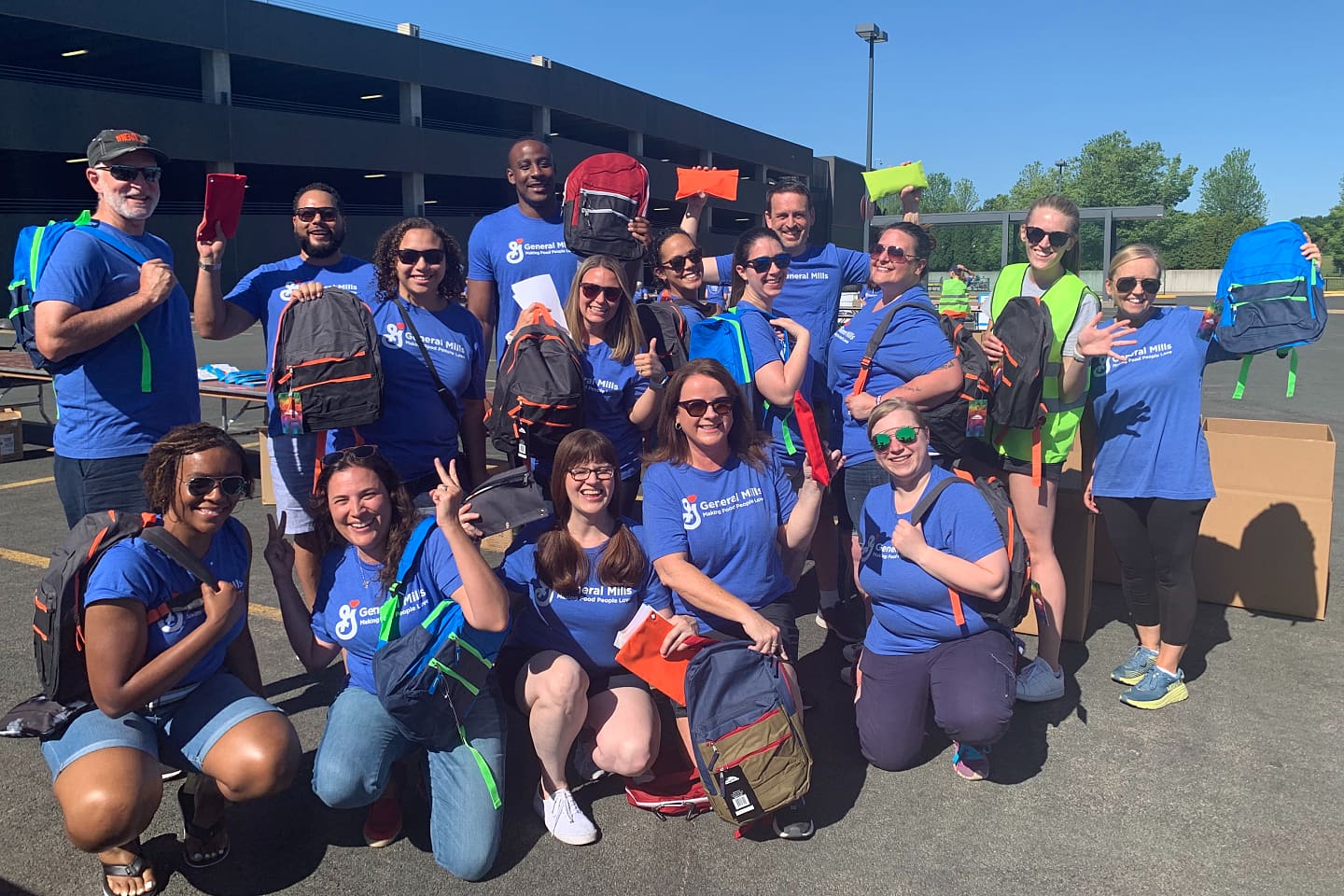 A group of employees holding backpacks up